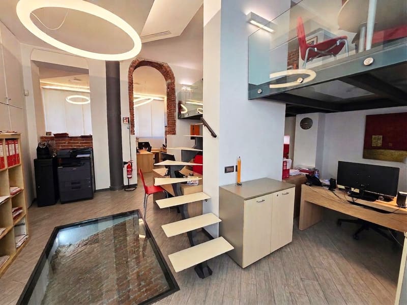 L'interno dello studio con la scala sospesa, il pavimento in vetro e l'arco in mattoni a vista